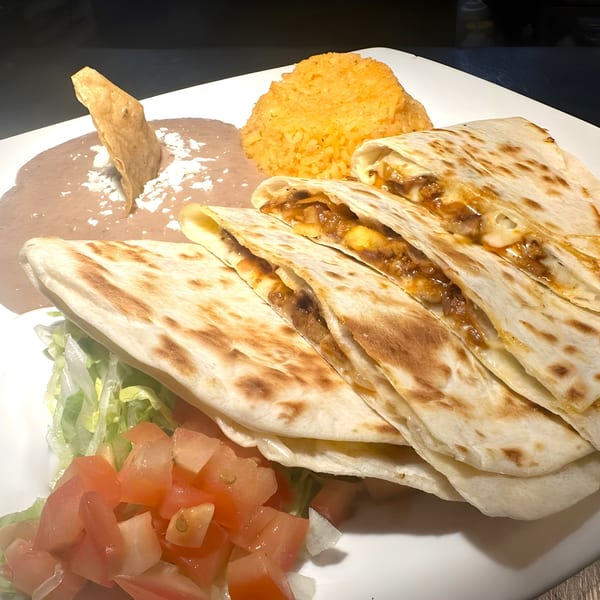 Javi Mexican Grill's quesadillas with rice, refried beans, lettuce, and diced tomatoes on a white plate.