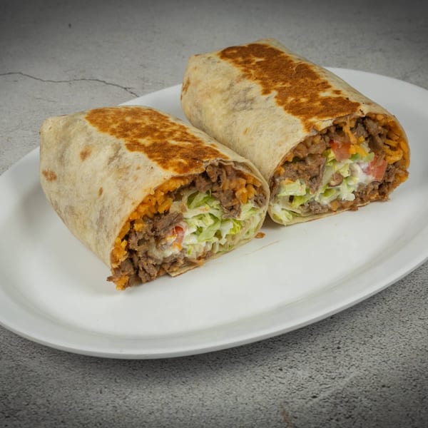 Two halves of a Javi Mexican Grill burrito, filled with meat, rice, lettuce, and sour cream.