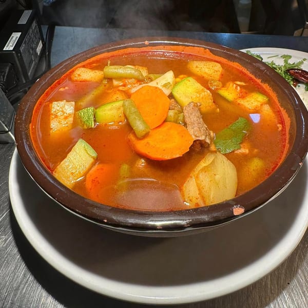 Steaming bowl of Javi Mexican Grill's hearty beef and vegetable soup with carrots, zucchini, and potatoes.