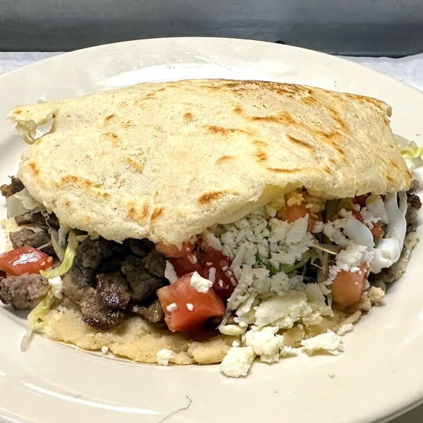 A Javi Mexican Grill gordita filled with steak, lettuce, tomatoes, crumbled cheese, and sour cream.